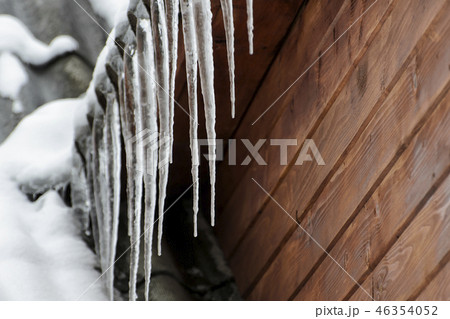 Icicles on a background of brown wooden wall 46354052