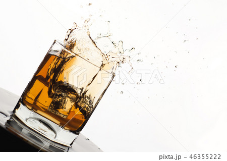 Tilted Glass of splashing whiskey with ice  46355222