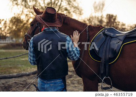 Brutal cowboy poses with horse, wild west Brutal cowboy poses with horse, wild west 46355719