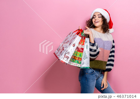 Beautiful women wearing bright Christmas carrying colorful shopping bags. On pink background 46371014