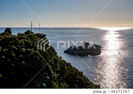 Sun path, small island and cross on sea hill 46373707
