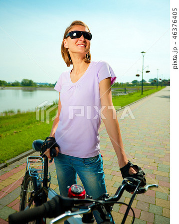 Young woman is standing behind bicycle 46376405