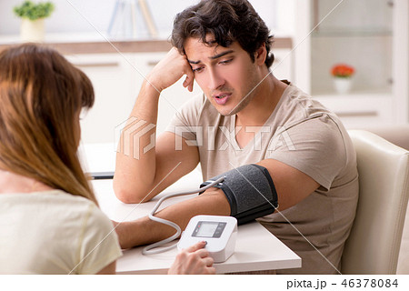 Wife checking husband's blood pressure Wife checking husband's blood pressure 46378084
