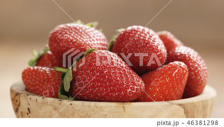 Closeup of fresh strawberries in bowl on wood table Closeup of fresh strawberries in bowl on wood table 46381298