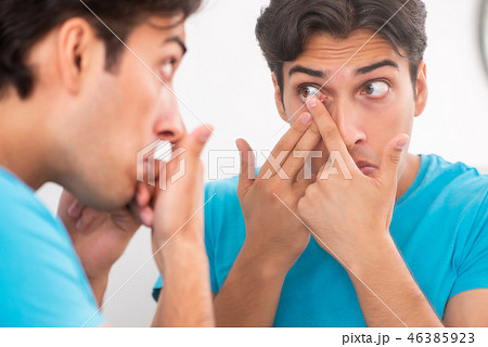 Man trying contact lenses at home 46385923