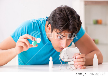 Man trying contact lenses at home Man trying contact lenses at home 46385952