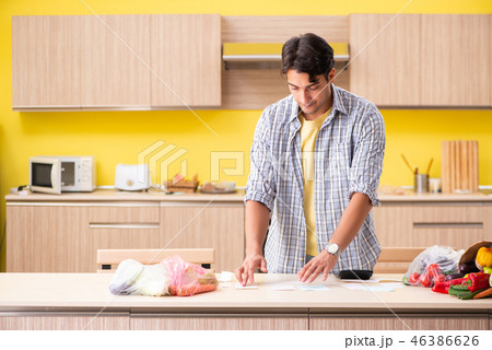 Young man calculating expences for vegetables in kitchen Young man calculating expences for vegetables in kitchen 46386626