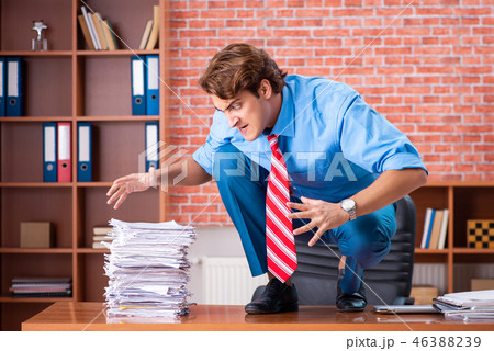 Young employee with excessive work sitting at the office Young employee with excessive work sitting at the office 46388239