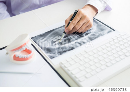 Concentrated dentist sitting at table with jaw samples tooth mod 46390738