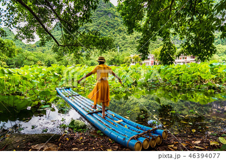 Girl on bamboo raft in lotus flower lake Girl on bamboo raft in lotus flower lake 46394077