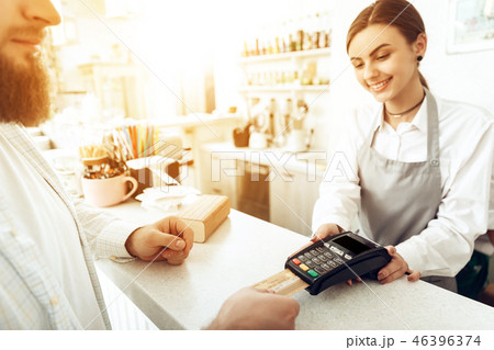 Cheerful cashier using digital device for payment Cheerful cashier using digital device for payment 46396374
