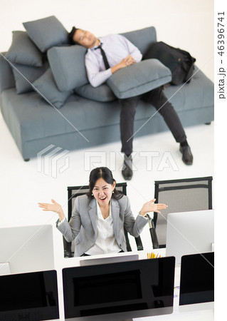Woman working, man napping at work. Woman working, man napping at work. 46396741