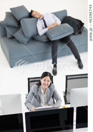 Woman working, man napping at work. Woman working, man napping at work. 46396744