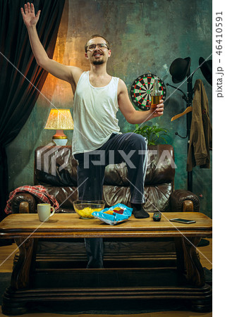 Winner. Overwhelmed cheerful man moving hands while celebrating the victory of a favourite football Winner. Overwhelmed cheerful man moving hands while celebrating the victory of a favourite football 46410591