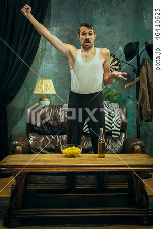 Winner. Overwhelmed cheerful man moving hands while celebrating the victory of a favourite football Winner. Overwhelmed cheerful man moving hands while celebrating the victory of a favourite football 46410625