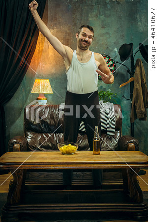 Winner. Overwhelmed cheerful man moving hands while celebrating the victory of a favourite football Winner. Overwhelmed cheerful man moving hands while celebrating the victory of a favourite football 46410627