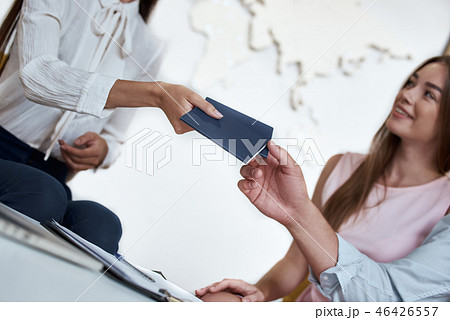 Travel agent and young couple. Young woman smiling and giving tickets, passport with visa to 46426557