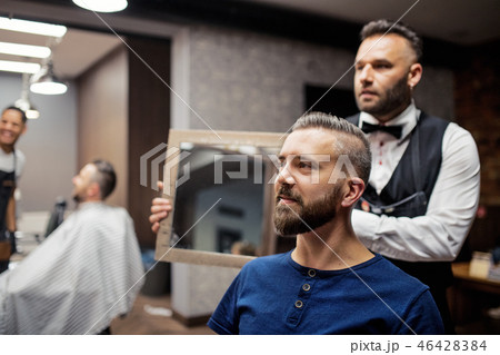 Hipster man client visiting haidresser and hairstylist in barber shop. 46428384