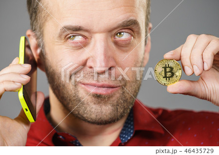 Man with bitcoin talking on phone Man with bitcoin talking on phone 46435729