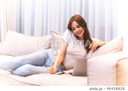 Busy joyous woman writing while being on sofa 46436626