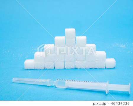 pile of white blocks of sugar and syringe insulin 46437335