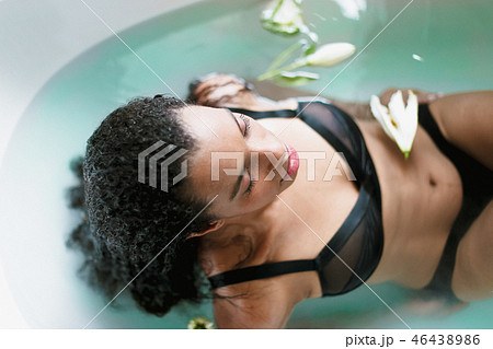 Young afro american female person taking bath and wearing black underwear, blue water background. 46438986