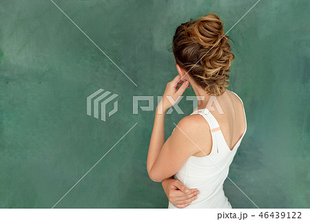 Young beautiful brunette with stylish hair smiles Think pose on a green background Young beautiful brunette with stylish hair smiles Think pose on a green background 46439122