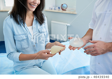 Smiling woman looking on breast implant in hospital 46439340