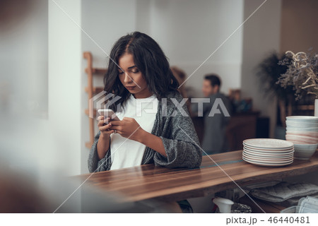 Calm lady standing at the bar counter and thoughtfully looking at smartphone Calm lady standing at the bar counter and thoughtfully looking at smartphone 46440481