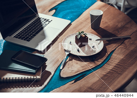 Unusual table with modern laptop and tasty cake on the plate on it 46440944