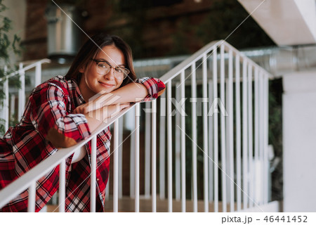 Charming lady in glasses leaning on stair railing Charming lady in glasses leaning on stair railing 46441452
