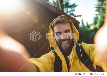 Traveler man making funny selfie near wooden house Traveler man making funny selfie near wooden house 46442074