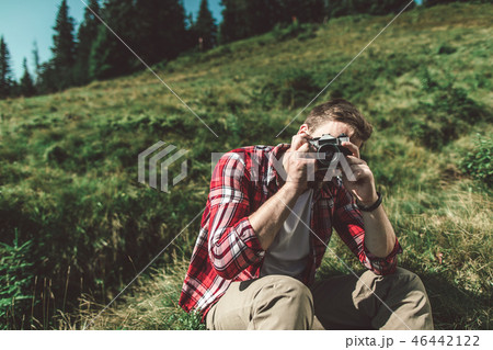 Traveler man taking shot by camera on green hill 46442122