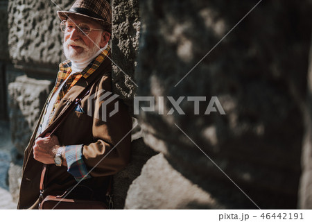 Hipster smiling old man leaning against building 46442191