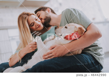 Youthful kissing couple embracing their slipping dog 46442990