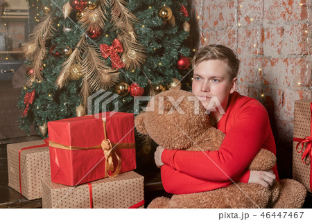 Handsome guy hugs the bear sitting under the tree 46447467