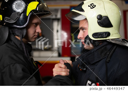 Photo of two firemen wearing helmets waving their handshake 46449347