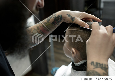 Children hairdresser cutting little boy against a dark background. Children hairdresser cutting little boy against a dark background. 46455675