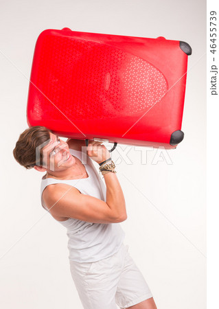 Expression and gesture concept - Young man in white shirt holding red suitcase Expression and gesture concept - Young man in white shirt holding red suitcase 46455739