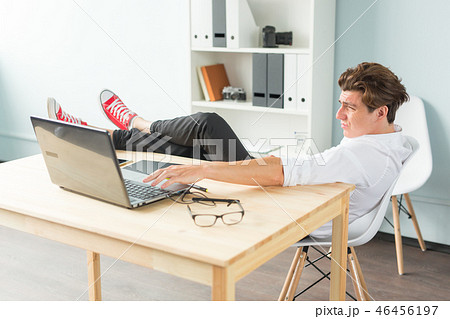 Relax, joke and business concept - handsome man having fun, sitting at the table with foot on it. Relax, joke and business concept - handsome man having fun, sitting at the table with foot on it. 46456197
