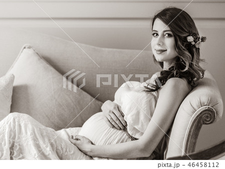 Young pregnant woman in white dress sitting Young pregnant woman in white dress sitting 46458112