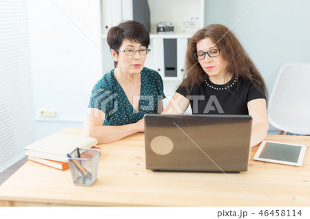 Business, technology and people concept - two women discuss a project watching in laptop 46458114
