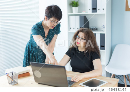 Business people, technology and communication concept - Mid-aged lady helping her female colleague Business people, technology and communication concept - Mid-aged lady helping her female colleague 46458145