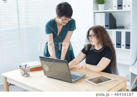 Business people, technology and communication concept - Mid-aged lady helping her female colleague Business people, technology and communication concept - Mid-aged lady helping her female colleague 46458187