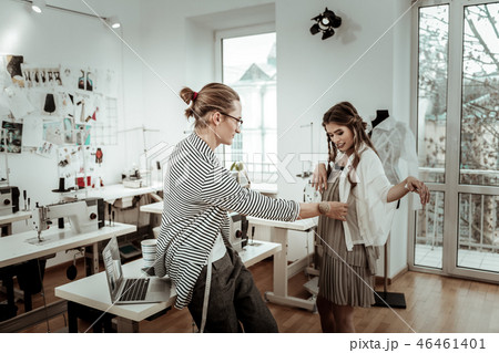 Tall handsome dressmaker in eyeglasses checking up a new dress 46461401