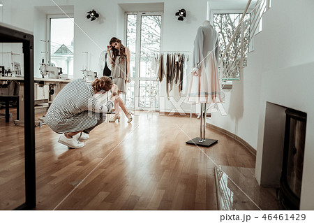 Long-haired fashion designer in a striped jacket making a picture of a model Long-haired fashion designer in a striped jacket making a picture of a model 46461429