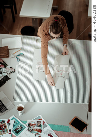 Tall fair-haired designer in a brown garment working with patterns Tall fair-haired designer in a brown garment working with patterns 46462389