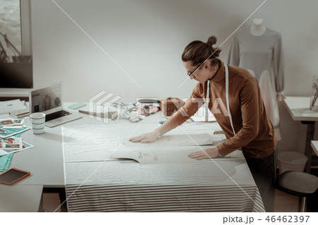 Tall professional designer in a brown garment getting ready for fabric cutting Tall professional designer in a brown garment getting ready for fabric cutting 46462397