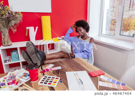 Fashion designer putting her legs on the table while looking at sketches 46467404