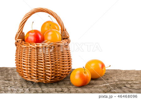 yellow plums with leaf in a wicker basket on wooden table with white background yellow plums with leaf in a wicker basket on wooden table with white background 46468096